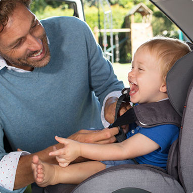 A father buckling his young son in to a toddlers car seat. A father buckling his young son in to a toddlers car seat.