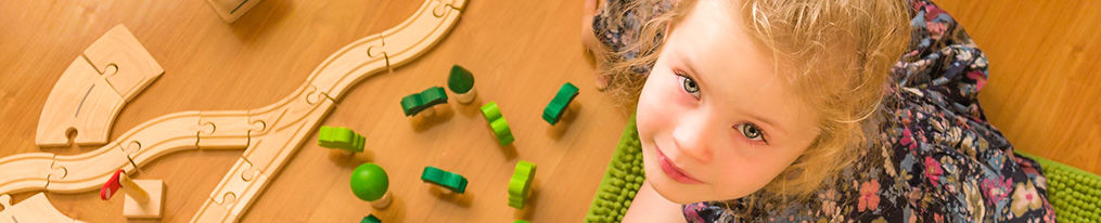 A young girl playing with her toys on the floor, looking upwards.