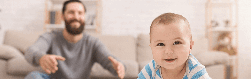 A baby crawling towards the camera with its parents sitting in the background.