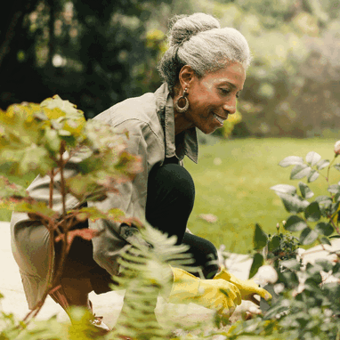 A late middle aged woman retrieving pots from her garden shed.