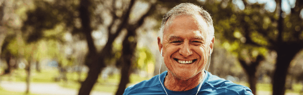 A middle aged man going for a jog through a park.