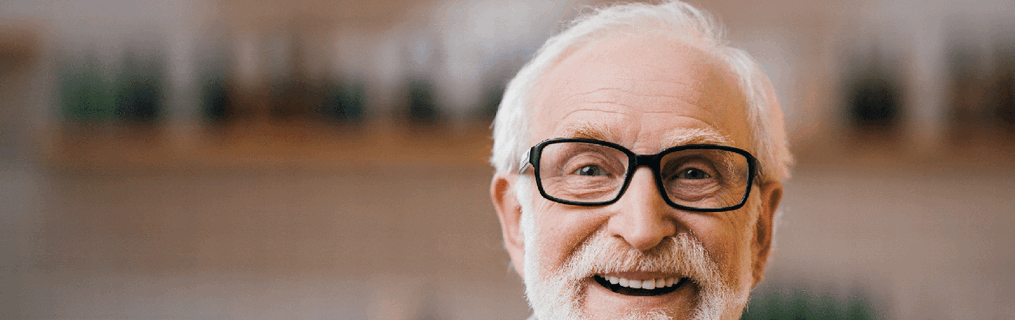 A smiling older man standing amongst products in a shop.