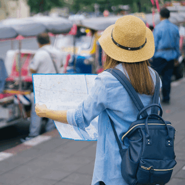 A young woman traveler walking outdoors with her backpack and straw hat.
