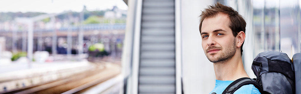 A young male traveler waiting at a train station.
