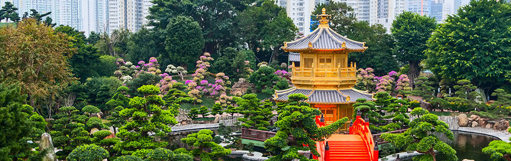 A traditional oriental building in parkland with the Hong Kong cityscape in the background.