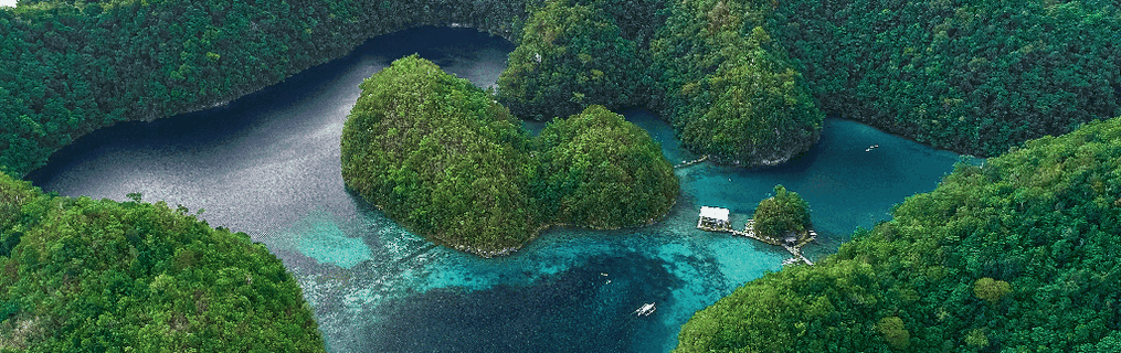 Wooden longboats anchored close by to a tropical island.
