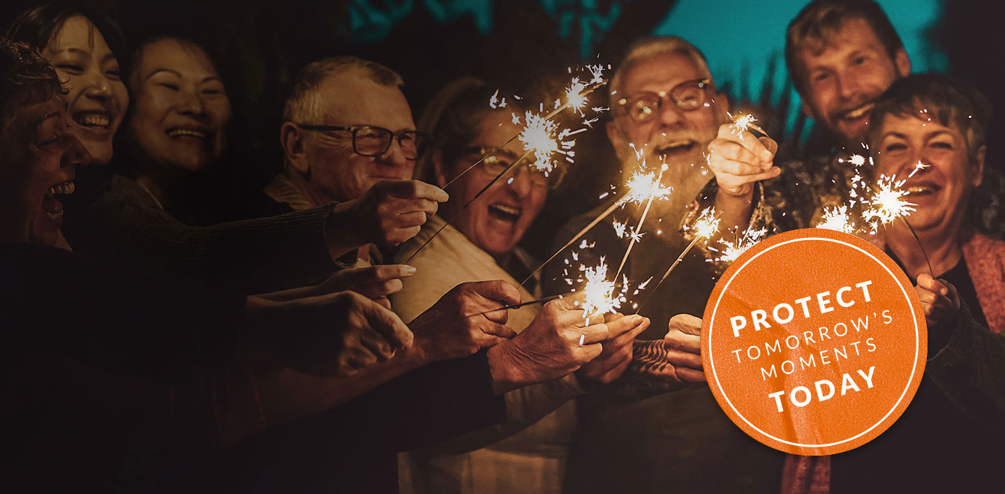 A group of eight older adults holding sparklers and laughing A group of eight older adults holding sparklers and laughing