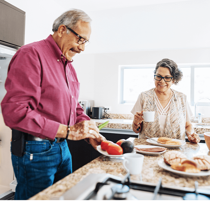 A man and woman smiling and preparing to eat breakfast at the kitchen countertop